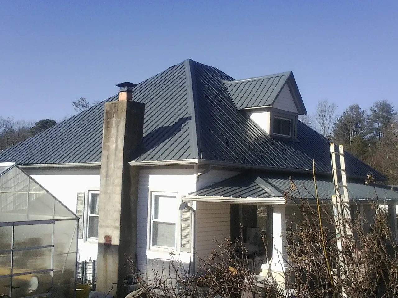Dark blue standing seam metal roof on a white farmhouse with dormer — Slate & Tile Roof Repair by Roofing Brothers in Wanatah
