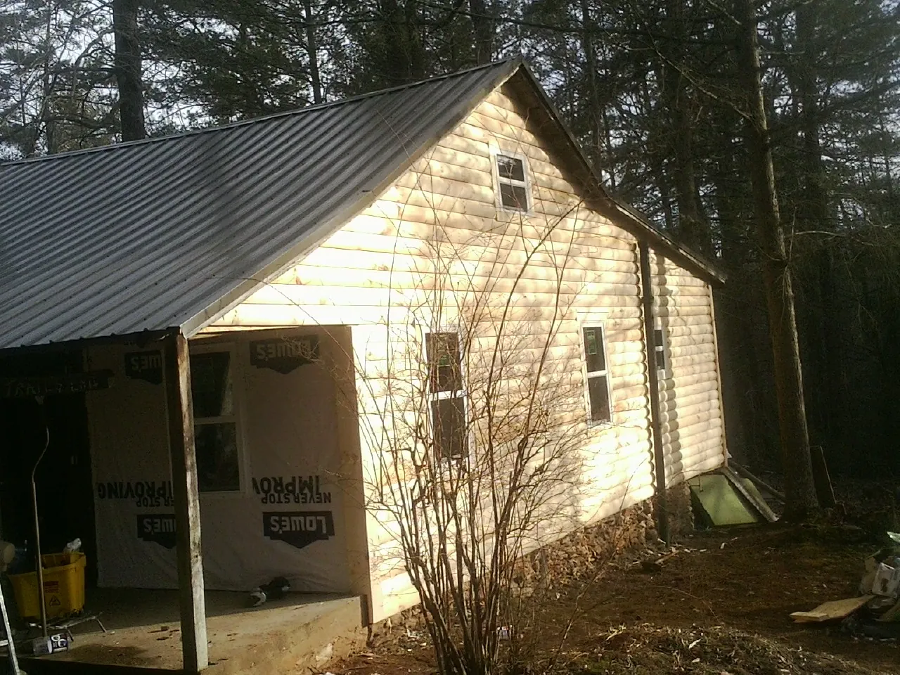 Log siding gable end under a dark metal roof edge in Wanatah
