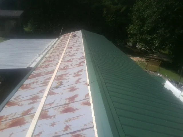 Old rusted panels beside newly installed green metal roofing — Wind Damage Roof Repair by Roofing Brothers in Wanatah