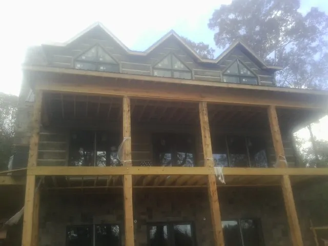 Dormers and porch framing on a large log home under construction — Roof Coating work by our crew in Wanatah