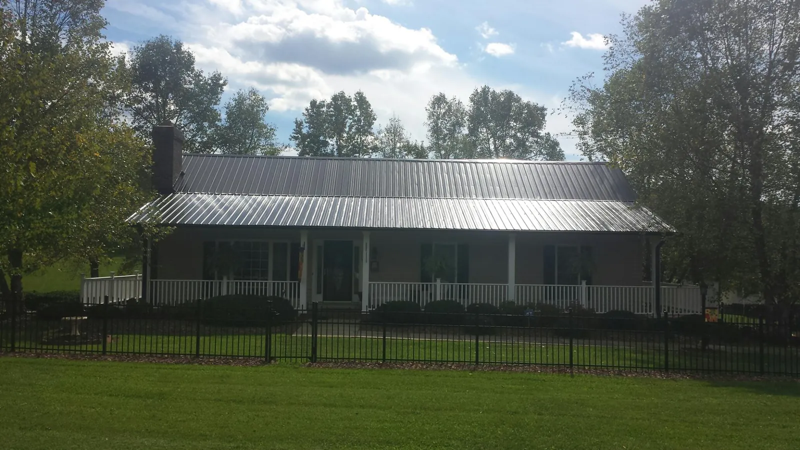 Gray metal roof on a brick ranch with a full width front porch — Gutter Guard Installation work by our crew in Wanatah