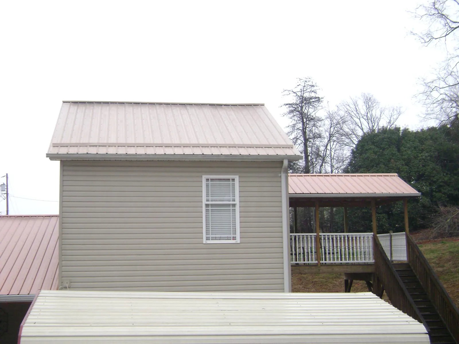 Tan metal roofs on a two story addition and attached porch, from a Roof Replacement job in Wanatah