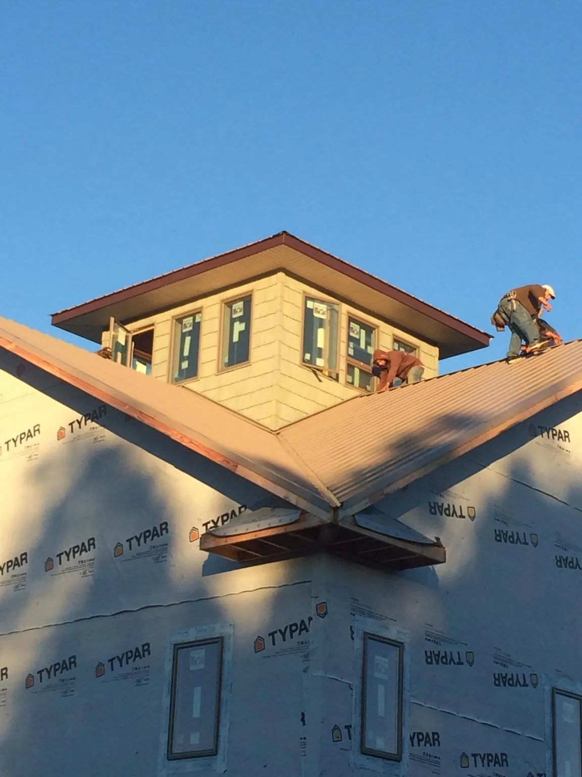 Roofers working around a rooftop cupola on a new metal roof at sunset — Roof Waterproofing in Wanatah by Roofing Brothers